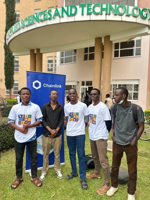 Five attendees posing in front of a Chainlink banner.