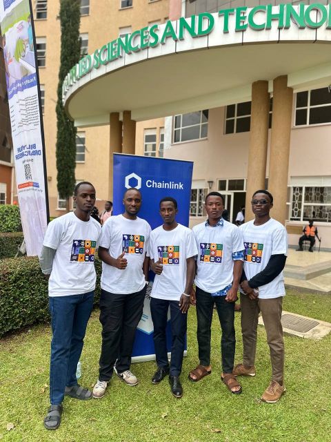 Five attendees in event T-shirts standing in front of the Chainlink banner.