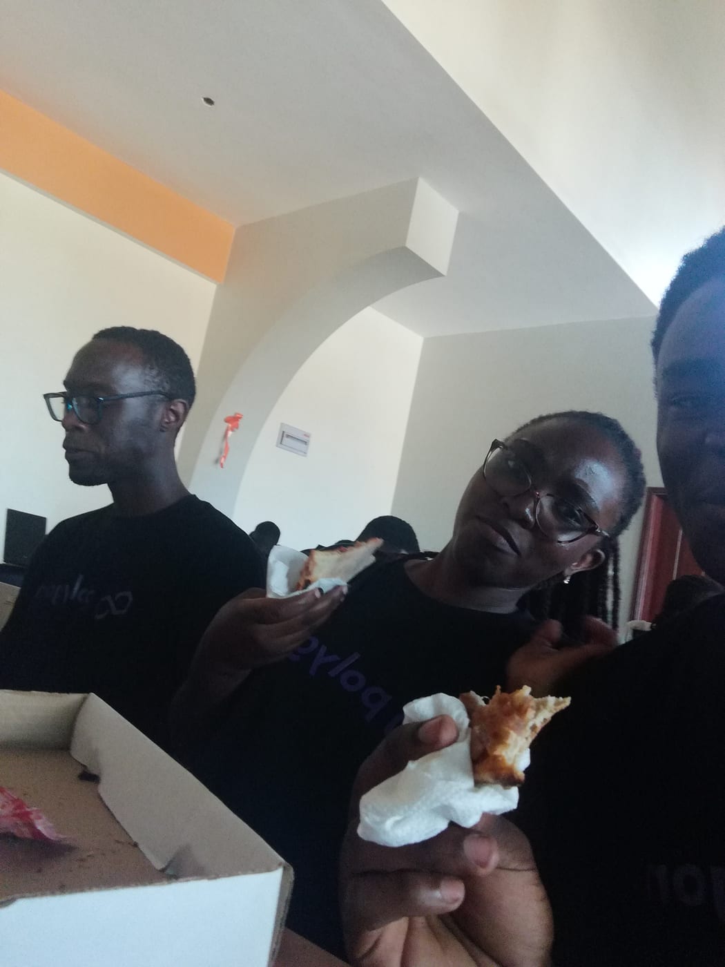 Attendees in Polygon shirts eating pizza during a break.